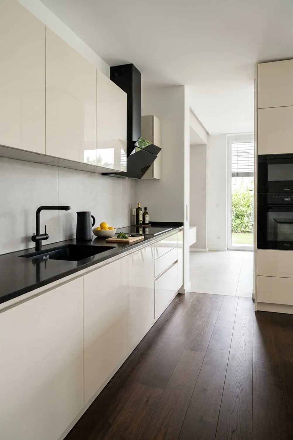 Eleganter Kontrast: Hochglanz-Fronten in Creme, schwarze Armaturen und ein dunkler Holzboden – Beige Küche: 10 wunderschöne Ideen