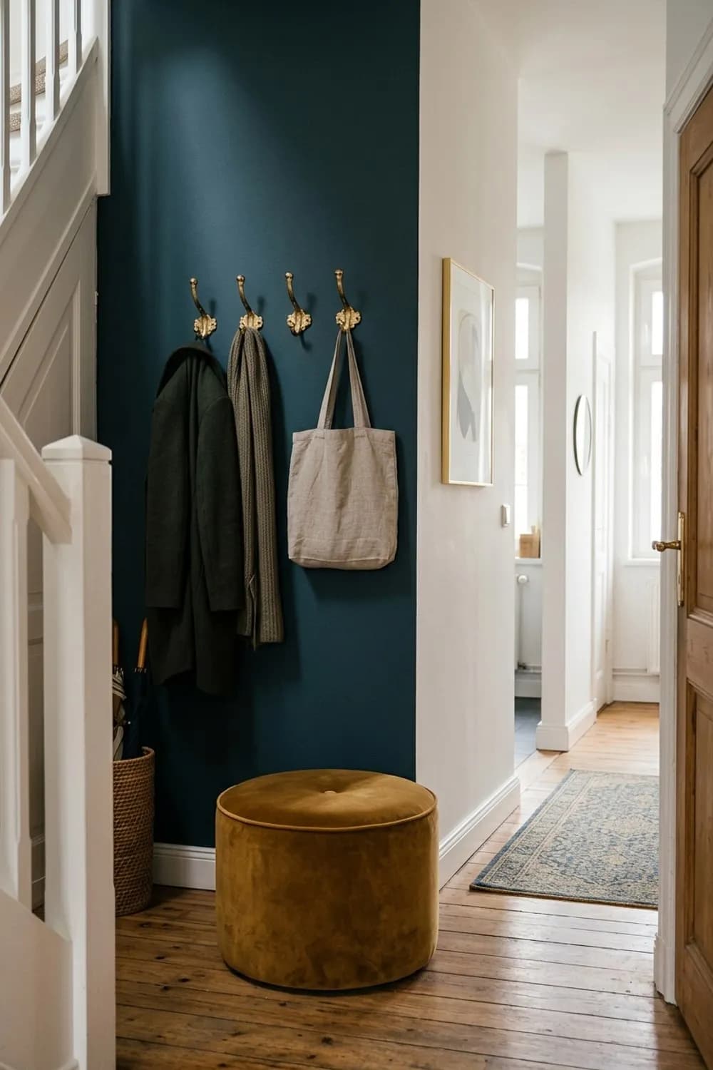 Dramatischer Akzent: Dunkle Wandfarbe, goldene Haken und ein Samt-Sitzpouf – Flur dekorieren: 9 schöne Ideen