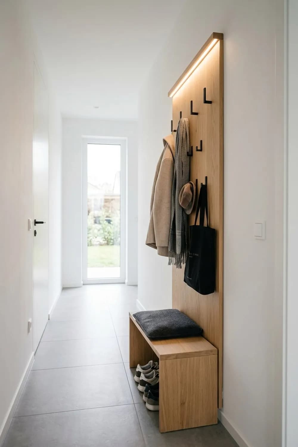 Die schwebende Lösung: Wandpaneel aus Holz, schwarze Haken und eine integrierte LED-Leiste – Garderobe im kleinen und schmalen Flur: 10 schöne Ideen